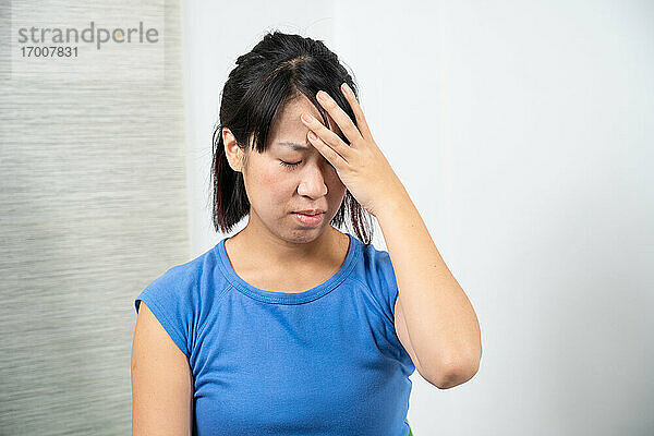 Asiatische Frau mit Kopfschmerzen.