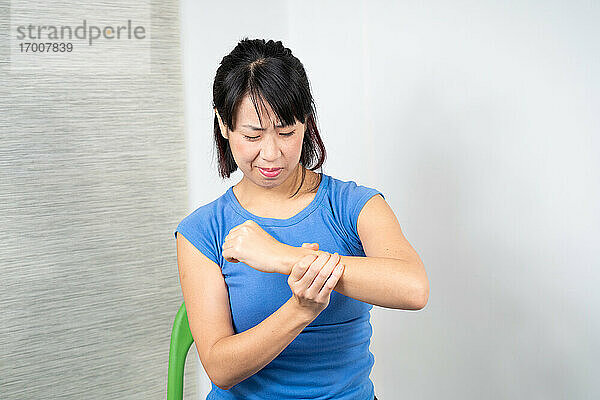 Asiatische Frau mit Schmerzen im Handgelenk