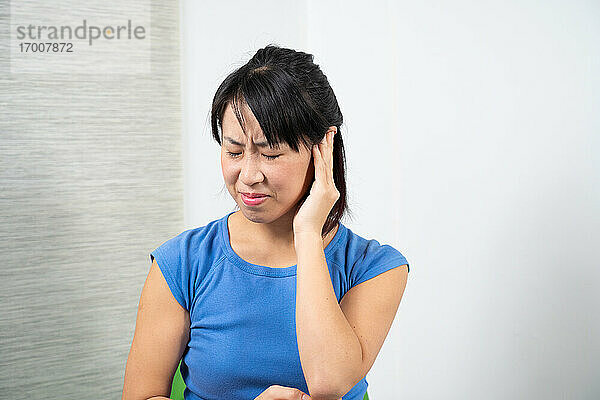 Asiatische Frau mit Ohrenschmerzen.