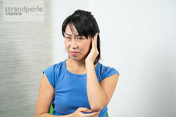 Asiatische Frau mit Ohrenschmerzen.