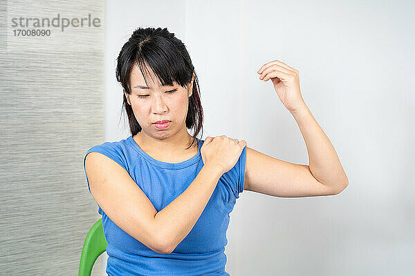 Asiatische Frau mit Schulterschmerzen