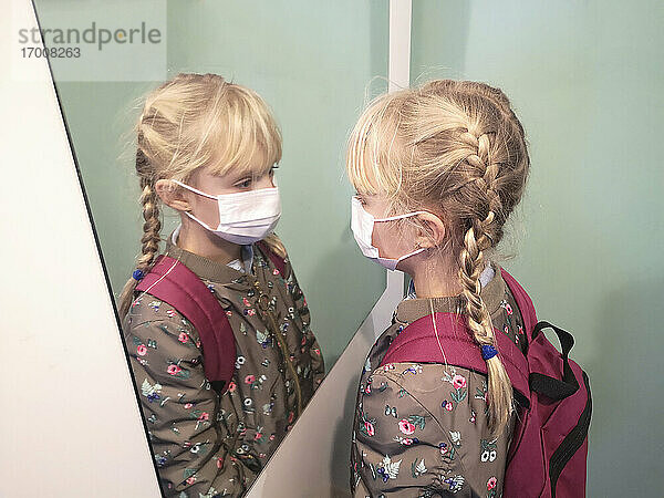 Maskiertes Mädchen im Alter von 7-11 Jahren  das sich vor dem Schulbesuch im Spiegel betrachtet  Frankreich  Europa.