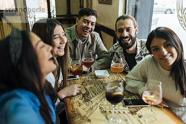 Männliche und weibliche Freunde lachen  während sie ein Selfie in einer Bar machen