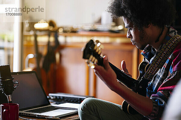 Männlicher Afro-Musiker  der zu Hause Gitarre übt