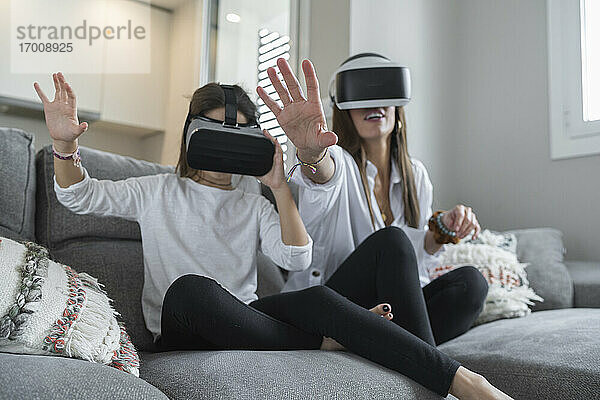 Tochter und Mutter machen eine Stop-Geste bei der Nutzung der virtuellen Realität im Wohnzimmer