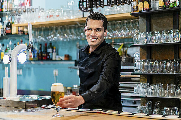 Porträt eines gutaussehenden Barkeepers  der Bier serviert