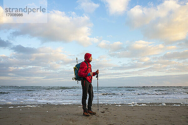 Mann mit Rucksack und Wanderstöcken am Strand stehend  Mittelmeer  Italien