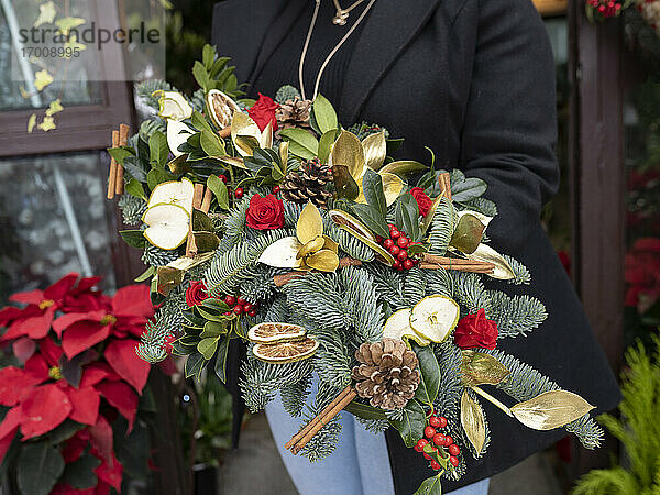 Florist mit Weihnachtsdekoration vor einem Blumenladen