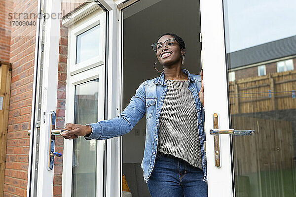 Lächelnde Frau beim Öffnen von Haustüren