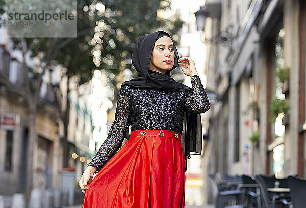 Porträt einer jungen Frau mit schwarzem Hidschab  die im Freien steht