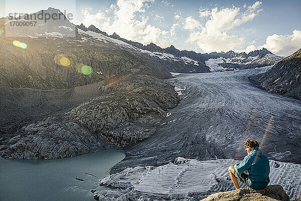 Schweiz  Wallis  Obergoms  Mann auf Felsen sitzend  mit Blick auf Rhonegletscher und Berge