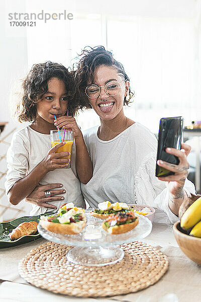 Mutter und Tochter machen ein Selfie beim Frühstück