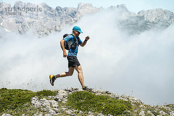 Älterer Sportler beim Trailrunning durch die nebligen Berge