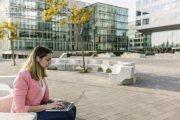 Spanien  Barcelona  Junge Geschäftsfrau mit Laptop vor einem Bürogebäude