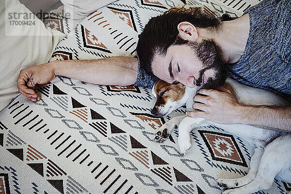 Mann schläft mit Hund auf dem Bett zu Hause