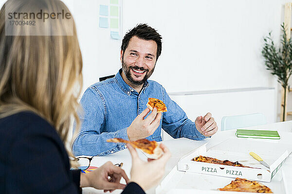 Geschäftsleute essen Pizza und unterhalten sich während der Pause im Büro