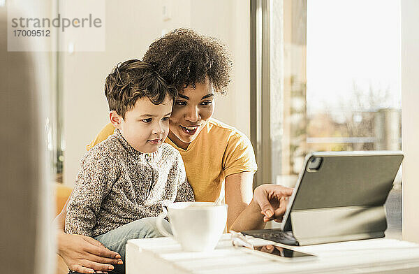 Frau unterrichtet Jungen mit Hilfe eines digitalen Tablets  während sie zu Hause sitzt