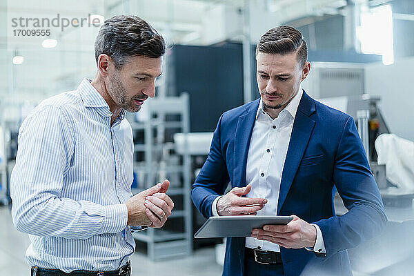 Geschäftsleute arbeiten gemeinsam an einem digitalen Tablet in der Industrie