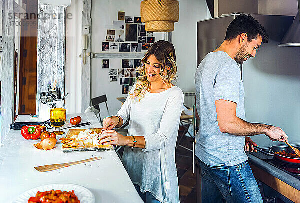 Glückliches junges Paar bei der gemeinsamen Zubereitung von Speisen in der Küche zu Hause
