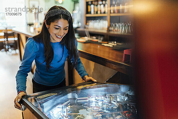 Attraktive Frau spielt Flipper in einer Bar