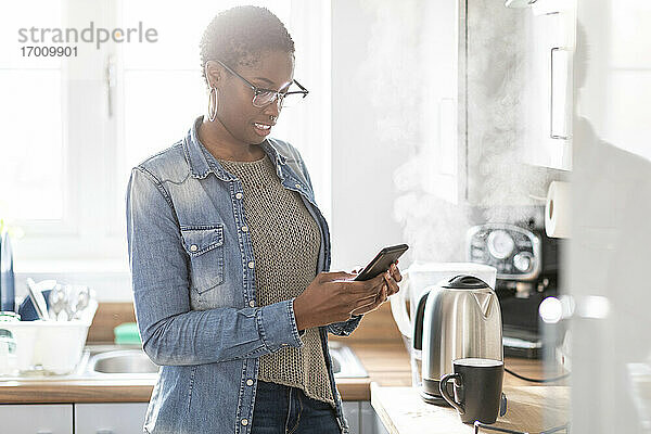 Frau benutzt Smartphone in der Küche
