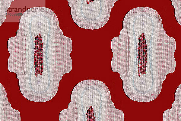 Muster von blutbefleckten Damenbinden vor rotem Hintergrund
