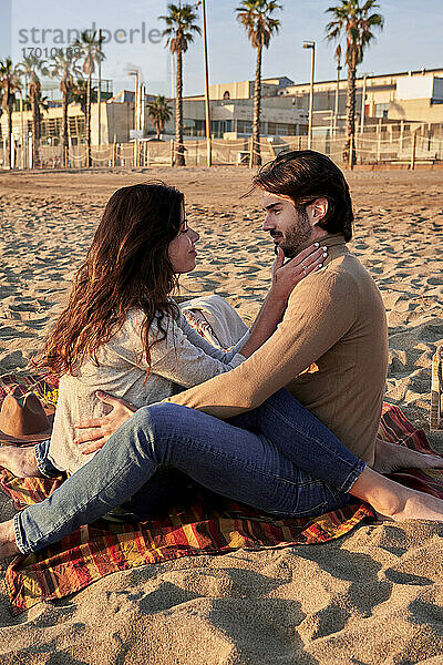 Junges Paar  das am Strand sitzt und eine Romanze hat