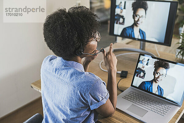 Frau hält Videokonferenz mit Kollegen über Laptop zu Hause