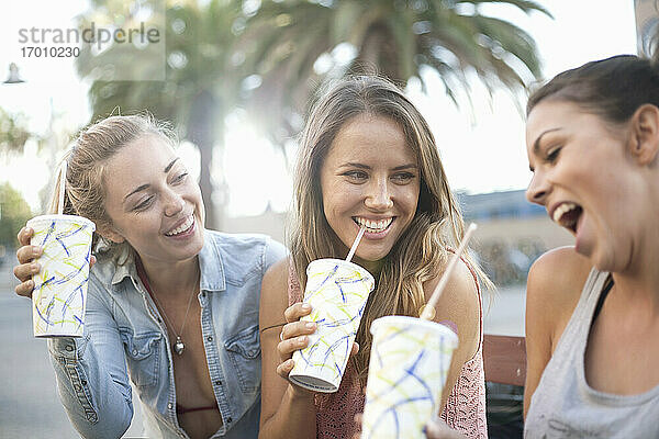 Unbekümmerte Freunde trinken im Urlaub am Strand gekühlte Getränke