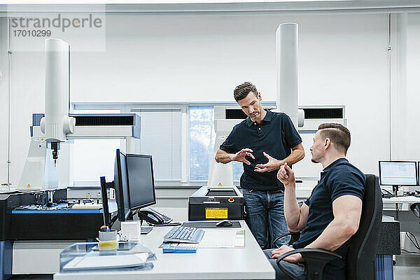 Männliche Ingenieure am Schreibtisch  die in einem Industriebüro diskutieren