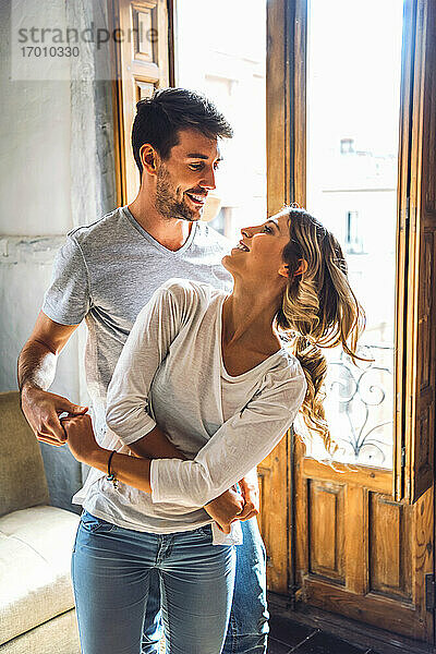 Verliebtes junges Paar tanzt zu Hause am Fenster