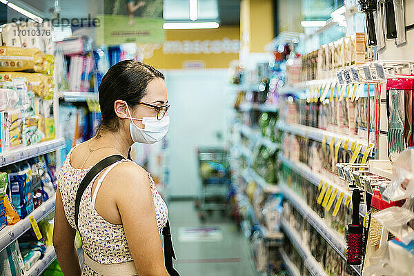 Mittlere erwachsene Frau mit Gesichtsschutzmaske im Supermarkt