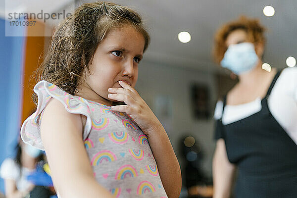 Aufgeregtes Mädchen  das den Friseur im Friseursalon während der Pandemie wegschaut