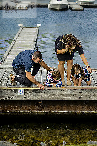 Familie schaut vom Pier aus aufs Wasser