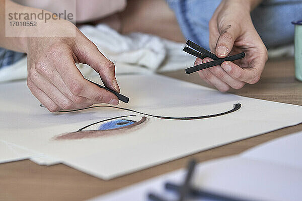 Künstlerin beim Zeichnen mit Kohle auf Papier im Wohnzimmer