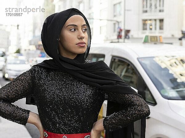 Porträt einer jungen schönen Frau mit schwarzem Hidschab  die auf der Straße posiert