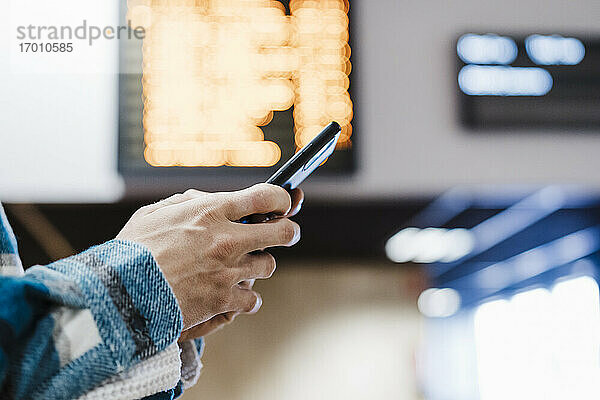 Nahaufnahme eines Mannes  der ein Mobiltelefon benutzt  während er in einer U-Bahn-Station steht