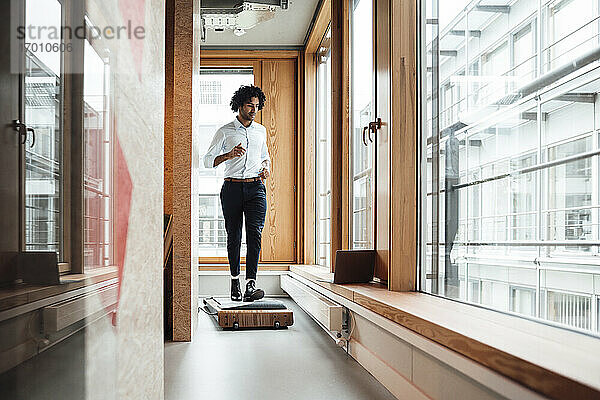Aktiver junger Geschäftsmann joggt auf einem Laufband vor einem Fenster am Arbeitsplatz