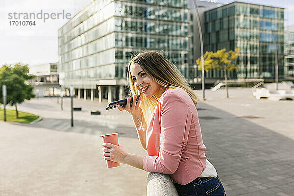Spanien  Barcelona  Lächelnde Frau beim Telefonieren in der Stadt