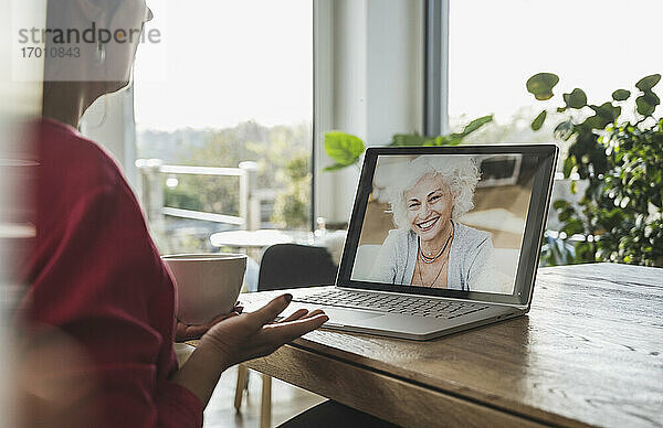 Ältere Frau lächelt während eines Videogesprächs auf dem Laptop-Bildschirm