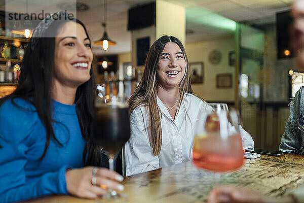 Lächelnde Freundinnen  die in einer Bar Getränke genießen