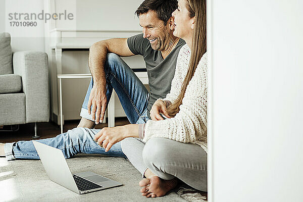 Glückliches reifes Paar  das lacht  während es zu Hause auf dem Laptop einen Film ansieht