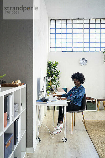 Frau arbeitet am Computer  während sie zu Hause im Büro sitzt