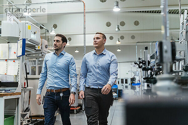 Männliche Inspektoren  die in einer Fabrik eine Maschine prüfen