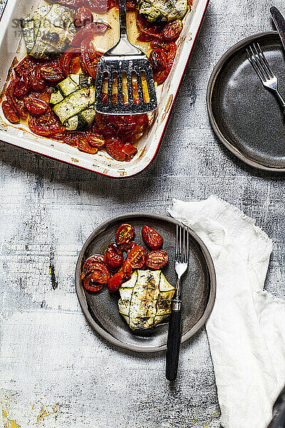 Gegrillte Tomaten mit Spinat und Feta-Käse gefüllte Zucchini-Ravioli im Teller mit Gabel auf dem Tisch