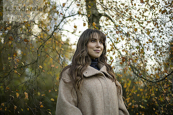 Schöne Frau in warmer Kleidung Tag träumen im Herbst Park