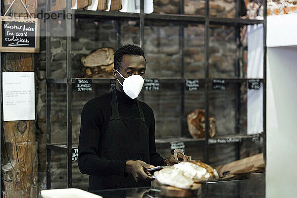 Bäckereibesitzer trägt Schutzmaske bei der Arbeit in der Bäckerei