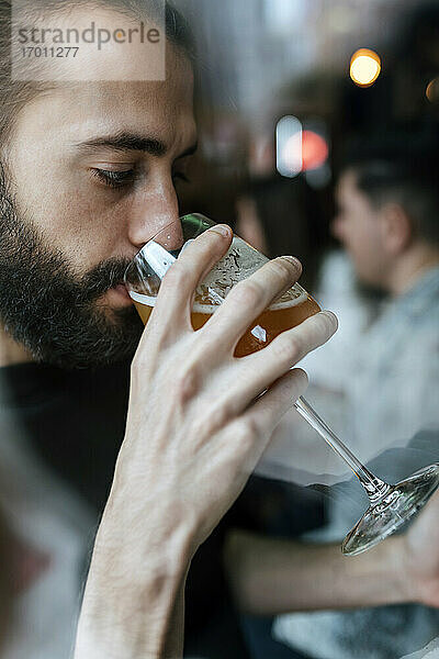 Junger Mann trinkt Bier in einer Bar