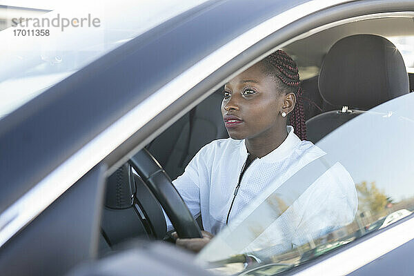 Junge Frau beim Autofahren durch das Fenster gesehen