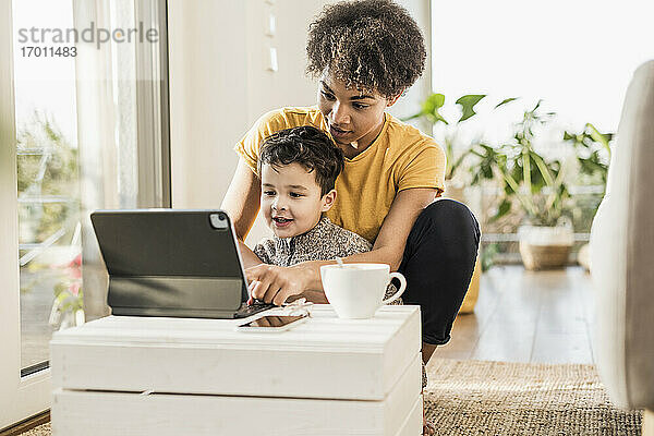 Mutter zeigt ihrem Sohn ein digitales Tablet  während sie zu Hause sitzt